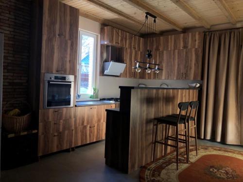 a kitchen with wooden cabinets and a bar with a microwave at Cozy Place in Kazbegi in Stepantsminda