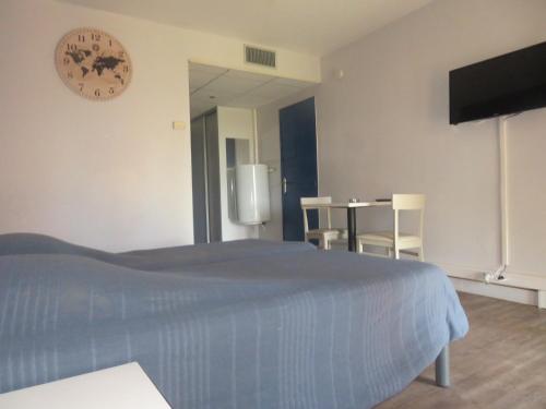 - une chambre avec un lit et une horloge murale dans l'établissement Appartement village 9 en résidence de vacances en Camargue, à Arles
