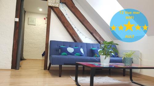 a blue couch in a living room with a table at Appartement centre village vue mer - Relais Fleuri in Ault
