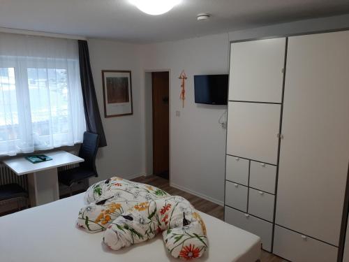a small room with a bed and a desk and a table at Pension Alpengruss in Heiterwang