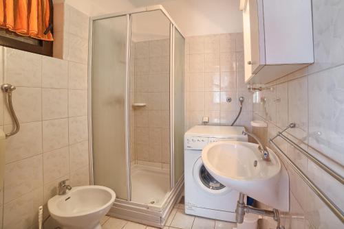 a bathroom with a shower and a sink and a washing machine at Apartment Villa Mare1 with pool, sea view and hydromassage in Banjole