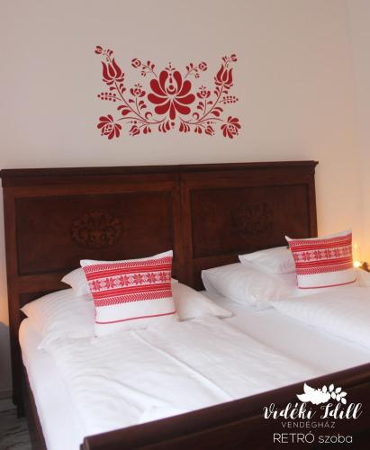 a bedroom with two beds with red and white pillows at Boutique Vendégház Vidéki Idill Noszvaj in Noszvaj