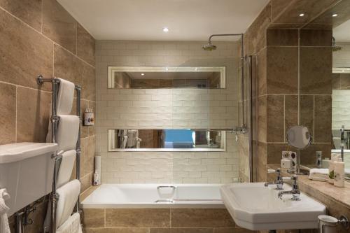 a bathroom with a tub and a sink and a bath tubermottermott at The Royal Oak Tetbury in Tetbury