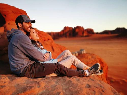 a man and woman sitting on a rock in the desert at WADI RUM STAR WARS CAMP in Wadi Rum