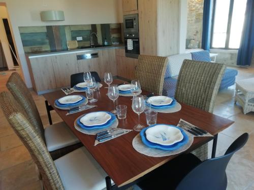 a wooden table with chairs and plates and glasses on it at Domaine de la Vidalle in Vendres