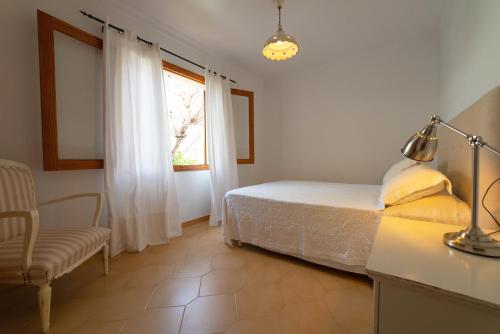 a bedroom with a bed and a chair and a window at Ca Na Capellá in Playa de Muro