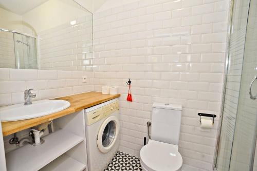 a bathroom with a toilet and a sink and a washing machine at White Rock Apartment by Grand Apartments in Sopot