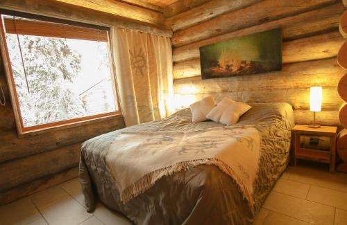 Un dormitorio con una cama en una cabaña de troncos en Villa Vuossel, en Ruka