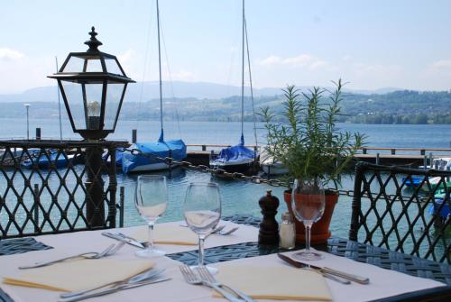 a table with glasses and utensils on a table with boats in the water at Hotel Hirschen am See in Meilen