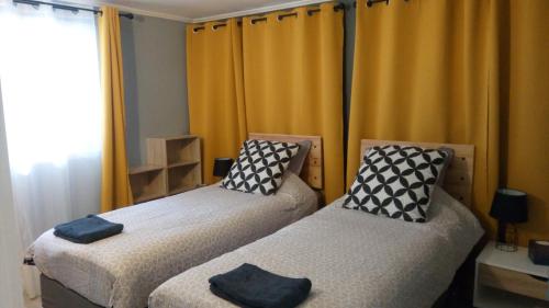 2 camas individuales en una habitación con cortinas amarillas en Bonne Nouvelle, en Saint-Jean-de-Maurienne