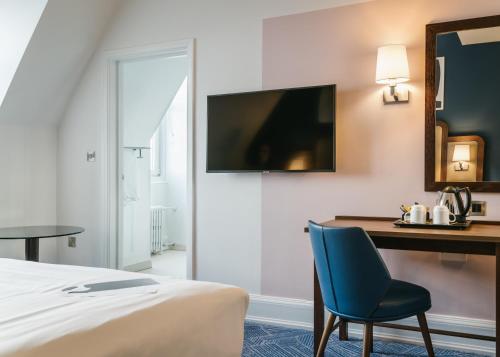 a hotel room with a bed and a desk and a chair at voco Grand Central Glasgow by IHG in Glasgow