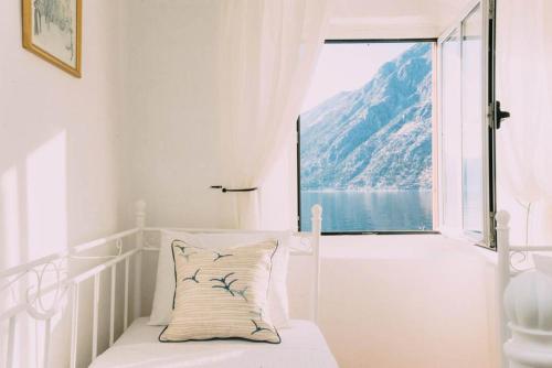 a white room with a bed and a large window at Casa Pasinovic in Kotor