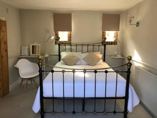 a bedroom with a black bed with pillows and a chair at The Admiral Hornblower in Oakham