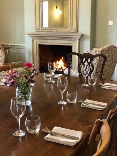 a wooden table with wine glasses and a fireplace at The Admiral Hornblower in Oakham