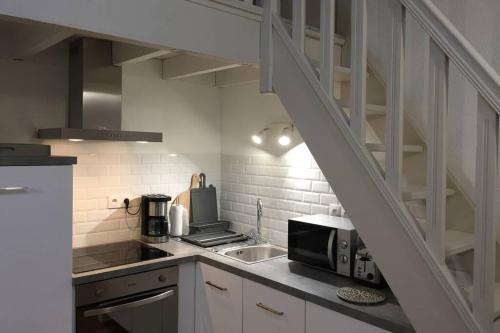 une cuisine avec un évier et un micro-ondes dans l'établissement Gîte Ste Cécile plage, à Camiers