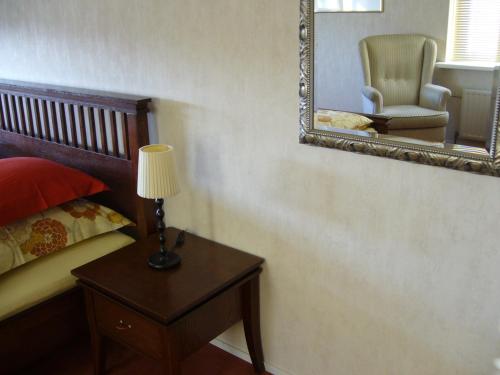 a bedroom with a table with a lamp and a chair at B&B Korendijk in Zuid-Beijerland