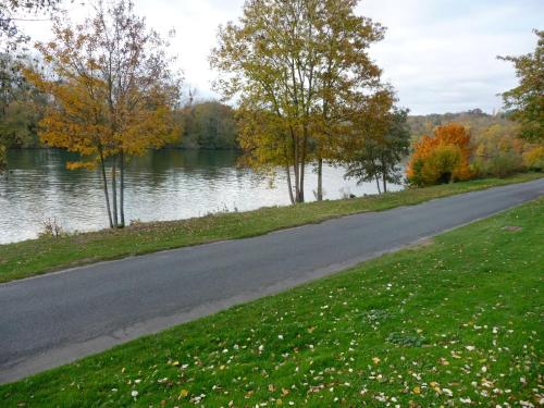 a road next to a body of water with trees at La Grande Maison in Seine-Port