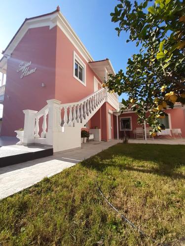 a pink and white house with a yard at Sugar Home in Xylokastro