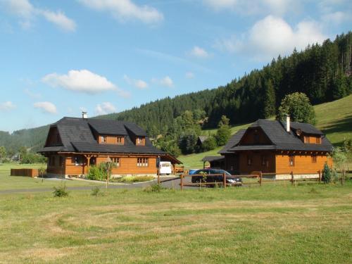 a couple of large wooden buildings in a field at Valašský dvůr in Velké Karlovice