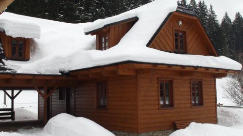a log cabin with snow on the roof at Valašský dvůr in Velké Karlovice