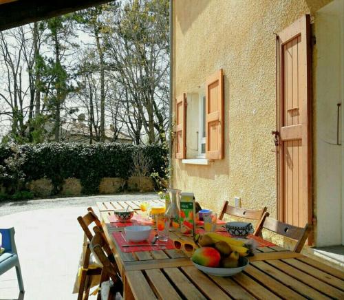 - une table en bois avec des fruits sur la terrasse dans l'établissement Maison 3 étoiles avec jardin pour familles, sportifs, curistes..., à Digne-Les-Bains