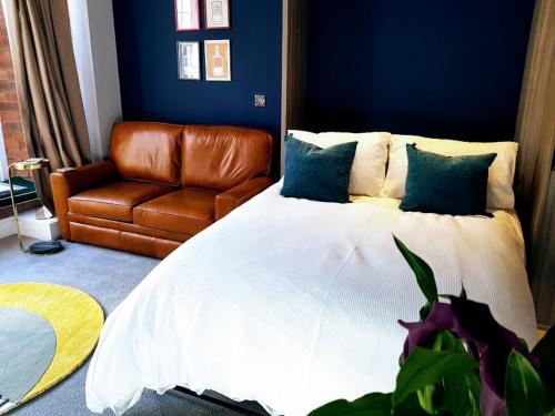 a bedroom with a bed and a leather couch at Cocoa Lily - River fronted studio with secure parking in York