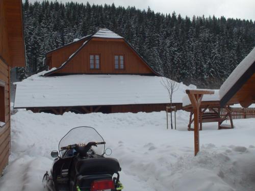 a snowmobile parked in the snow in front of a cabin at Valašský dvůr in Velké Karlovice