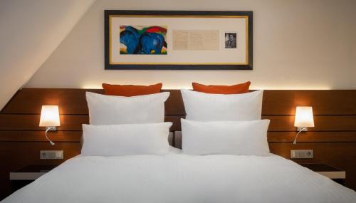 a bedroom with a bed with white sheets and orange pillows at Hotel zur Post Riesenbeck in Riesenbeck