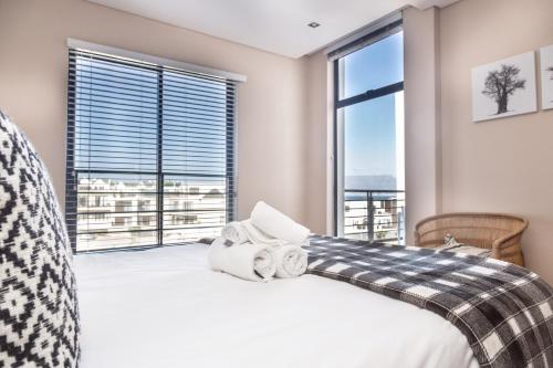 een slaapkamer met een bed en een groot raam bij Eden on the Bay Luxury Apartments, Blouberg, Cape Town in Bloubergstrand