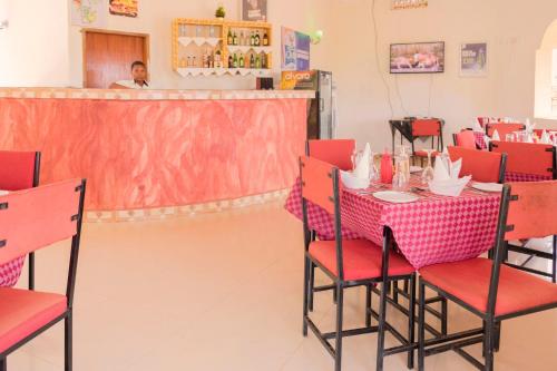 een restaurant met een tafel met rode stoelen en een serveerster bij Jaguar Hotel Kampala in Kampala