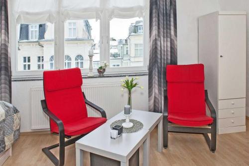 duas cadeiras vermelhas e uma mesa num quarto com uma janela em Villa Seestern Wohnung 9 em Neuhof