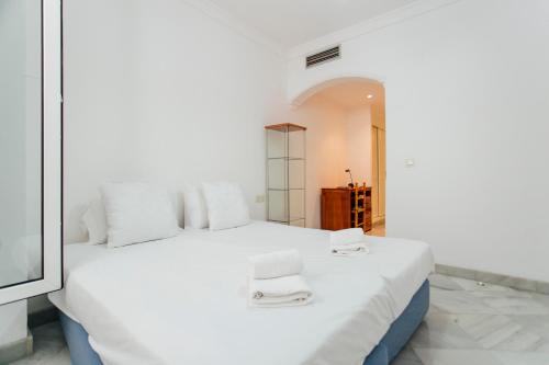 a bedroom with a white bed with two stools on it at Cozy and bright- 1Bd 1Bth - La Alfalfa in Seville