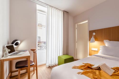 a hotel room with a bed and a desk and a window at 9Hotel Republique in Paris