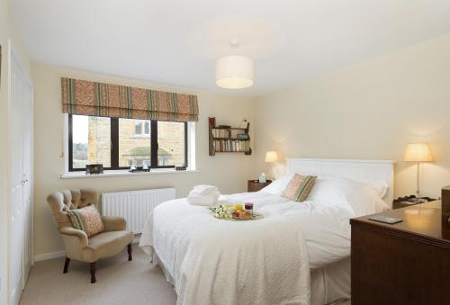 1 dormitorio con cama, silla y escritorio en Fairfields, en Moreton-in-Marsh