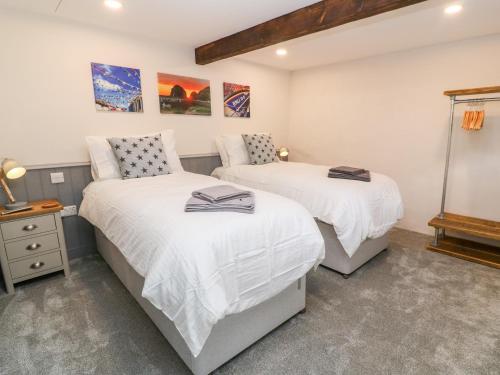 two beds in a bedroom with white walls at Nana's Cottage in Camborne