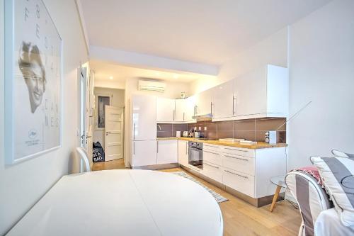 une cuisine avec des armoires blanches et une table dans l'établissement Cannes Carré d'Or Cozy 1 BR balcony, Croisette Palais 2 mn by Olam Properties, à Cannes