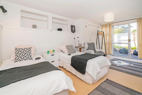 a bedroom with two beds and a chair and a window at Patton's Place - Pauanui Holiday Home in Pauanui