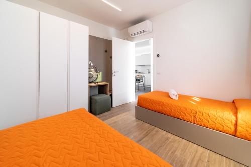 two beds in a bedroom with orange sheets at Residenza Olivo in Garda