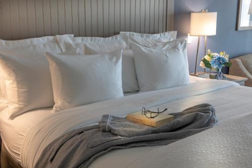 a bed with a book and glasses on it at Chautauqua Harbor Hotel - Jamestown in Celoron