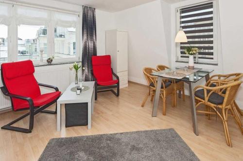 uma sala de estar com cadeiras vermelhas e uma mesa em Villa Seestern Wohnung 9 em Neuhof