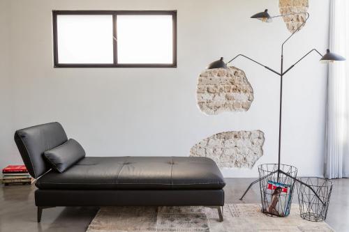 a black leather couch in a living room with a window at The Wall by HolyGuest in Tel Aviv