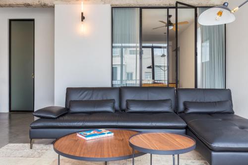 a living room with a black leather couch and a table at The Wall by HolyGuest in Tel Aviv