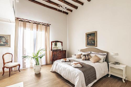 a white bedroom with a large bed and a chair at Giulio Cesare 14, Residence in Palermo