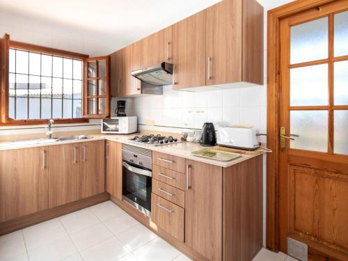 a kitchen with wooden cabinets and a stove top oven at Holiday Home Las Haciendas by Interhome in Alcossebre