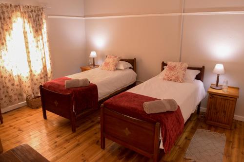 een slaapkamer met 2 bedden, een raam en houten vloeren bij Karoo Secret in Aberdeen