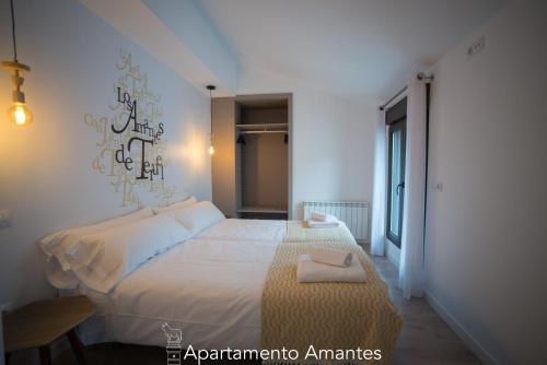 a bedroom with a white bed with a sign on the wall at Apartamentos Plaza del Torico Teruel in Teruel