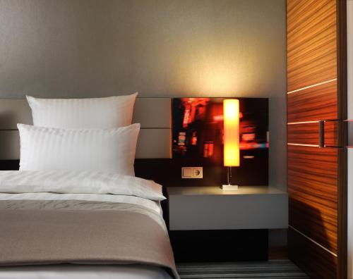 a bedroom with a bed and a tv on a wall at Steigenberger Airport Hotel Frankfurt in Frankfurt