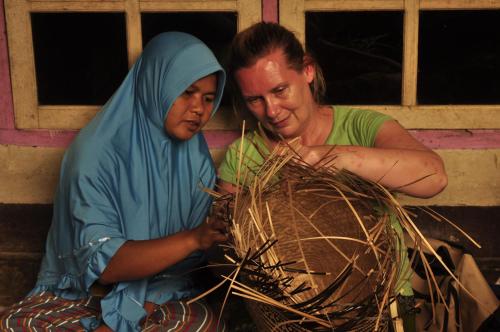 two women sitting next to each other making a nest at Mu Homestay in Tetebatu