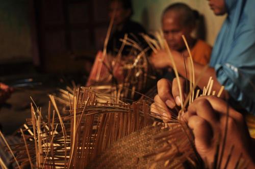 a group of people working on a table with sticks at Mu Homestay in Tetebatu