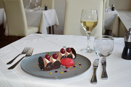 a plate of desserts on a table with a glass of wine at Hôtel la Prairie in Yverdon-les-Bains
